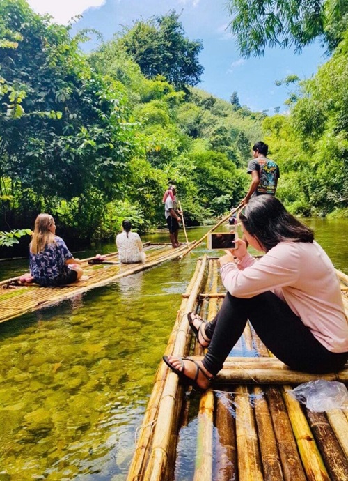 People on a bamboo raft on a shallow river through the jungle