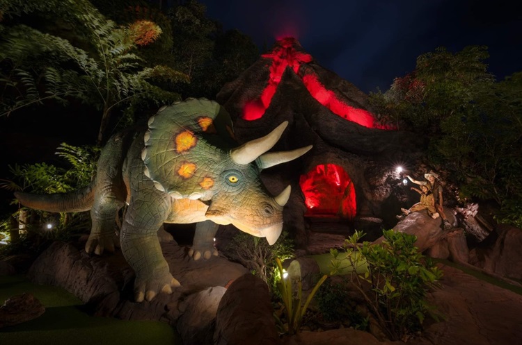 A dinosaur in Dino Park with an erupting volcano in the background