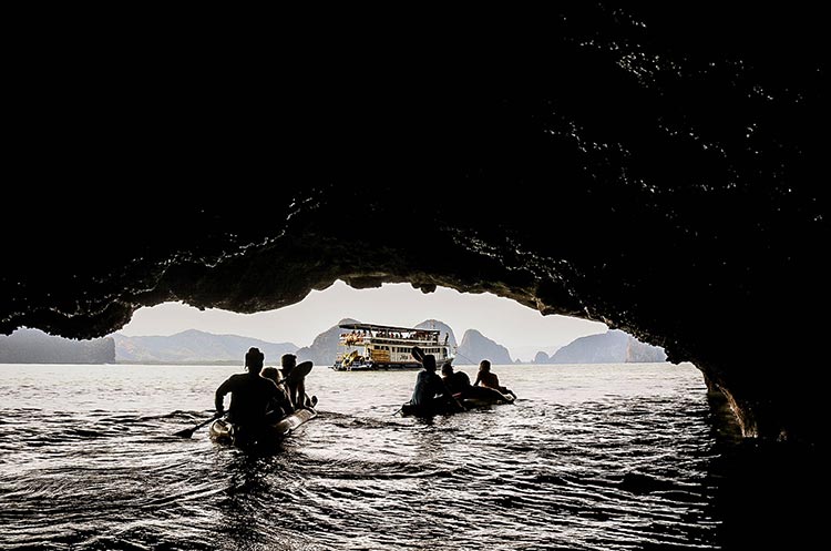 Sea canoes paddling out of a sea cave towards the John Gray support ship