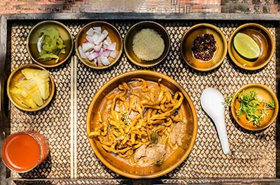 A bowl of Khao Soi and several condiments