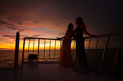 Two women on deck of the Melody ship while the sun sets in the Andaman Sea