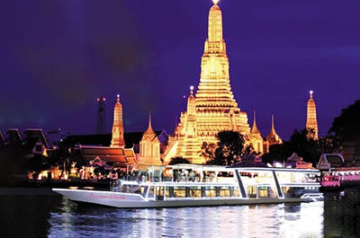 The River Star Princess dinner cruis ship sailing past the illuminated Wat Arun on the west bank of the Chao Phraya river